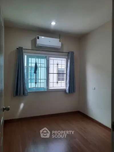 Cozy bedroom with wooden flooring and air conditioning, perfect for comfortable living.