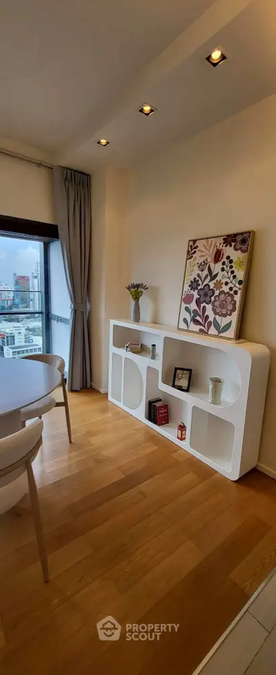 Stylish modern living room with wooden flooring and city view from large window.