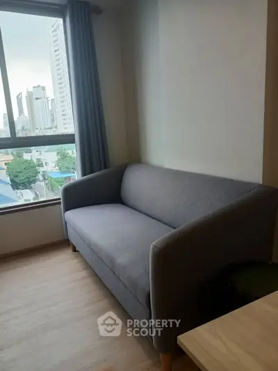 Cozy living room with modern sofa and city view window, perfect for urban living.
