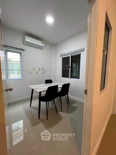 Modern study room with sleek table and chairs, featuring large windows and air conditioning.