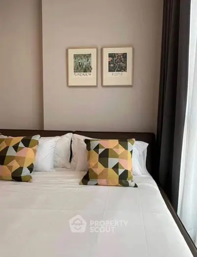 Modern bedroom with geometric pillows and framed art, showcasing a cozy and stylish interior design.