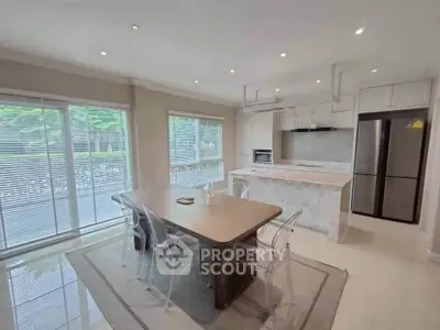 Spacious modern kitchen with open layout and elegant dining area, featuring large windows and sleek appliances.