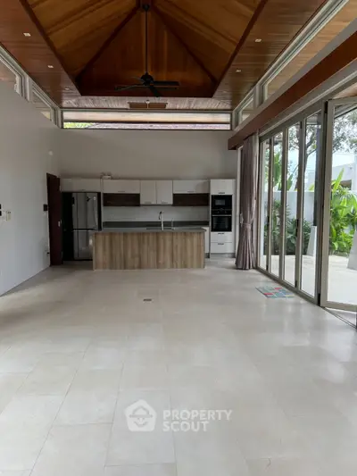 Spacious open-layout kitchen with modern appliances and large windows overlooking greenery.