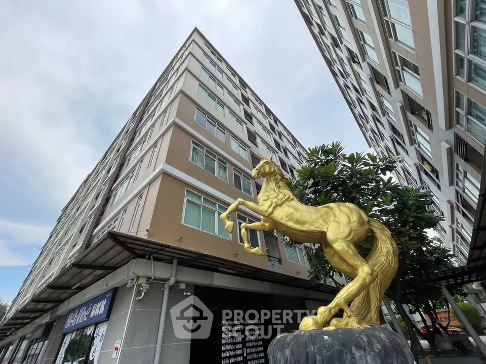 Modern apartment building with unique golden horse statue in urban setting.