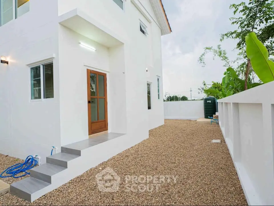 Modern white house exterior with gravel yard and wooden door entrance
