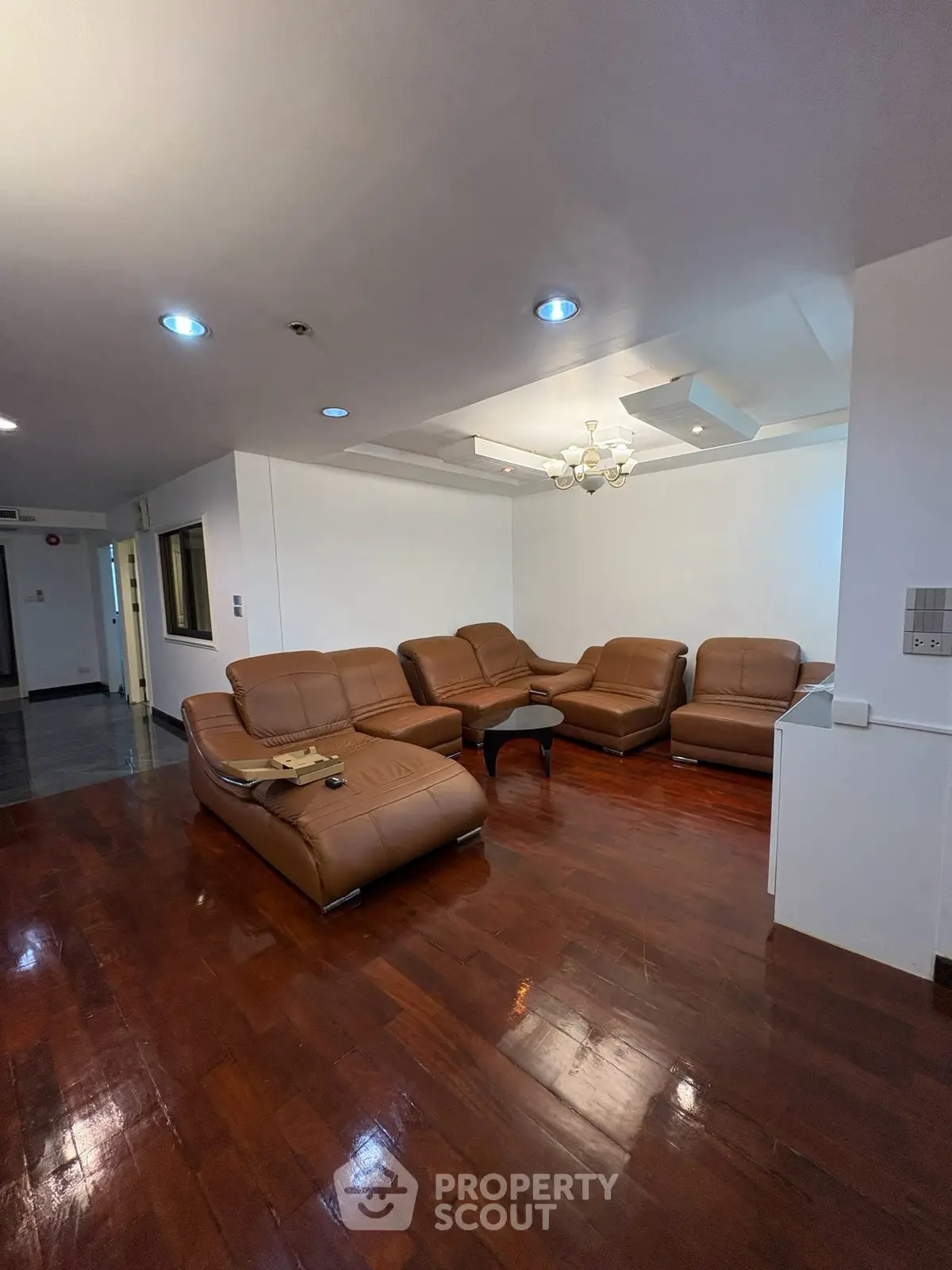Spacious living room with elegant leather sofas and wooden flooring, perfect for relaxation and entertainment.