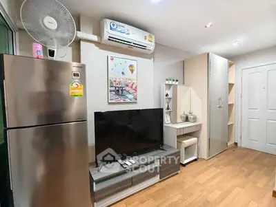 Modern living room with sleek furniture and appliances, featuring a TV and air conditioning.