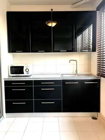 Modern kitchen with sleek black cabinets and microwave, perfect for contemporary living.