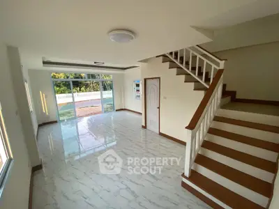 Spacious modern living room with staircase and large windows offering natural light and garden view.