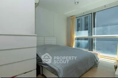 Bright and cozy bedroom with large window and modern furnishings.