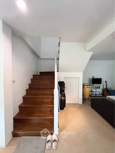 Stylish modern living room with wooden staircase and musical instruments, perfect for creative living.