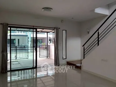 Spacious modern living room with sliding glass doors and sleek staircase, ideal for contemporary living.