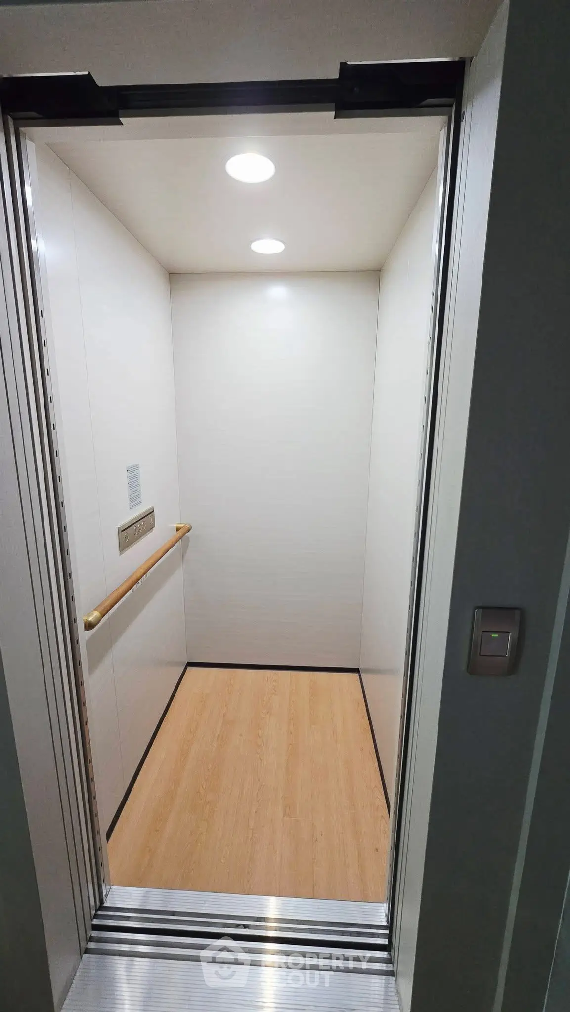 Modern elevator with sleek design and wooden flooring in a residential building.