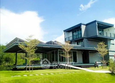 Modern architectural home with expansive glass windows and lush green lawn