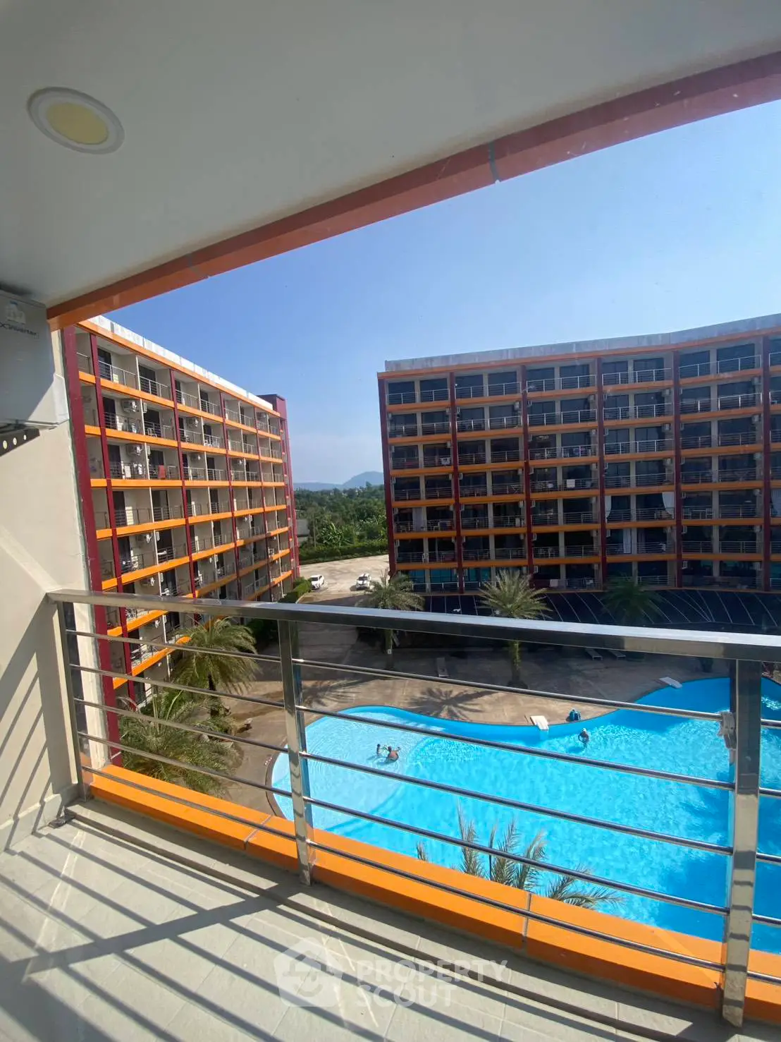 Stunning balcony view of modern apartment complex with pool and lush surroundings.