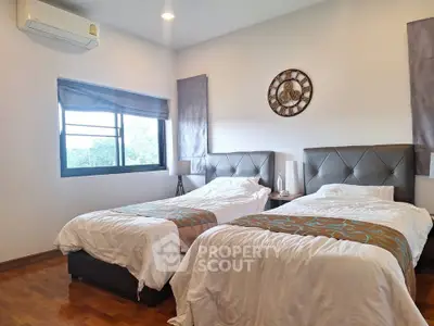 Spacious bedroom with twin beds and elegant decor, featuring a large window for natural light.