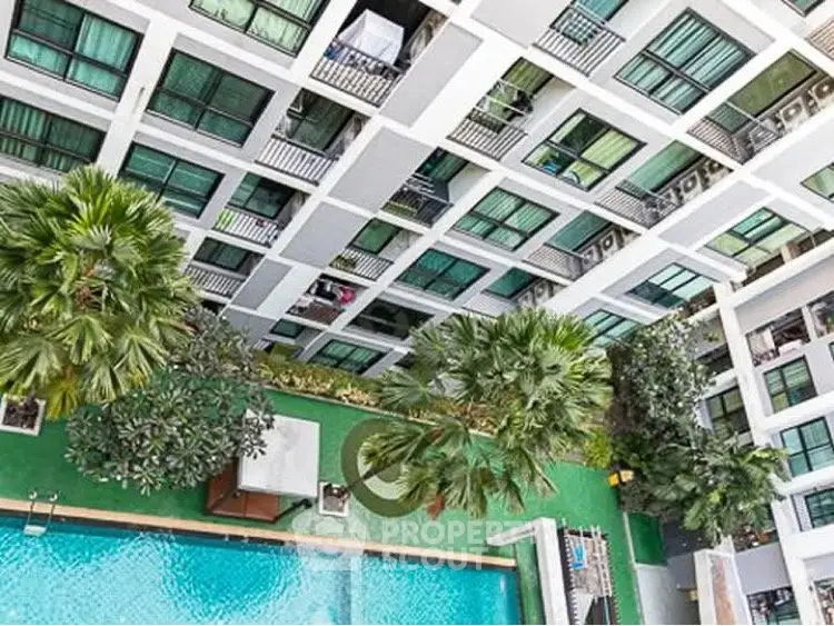 Stunning aerial view of modern apartment complex with lush greenery and inviting swimming pool.