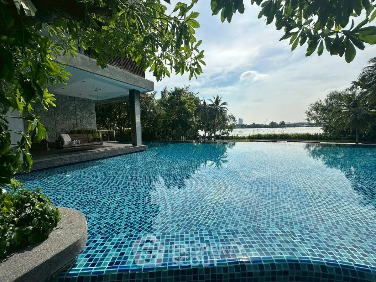 Luxurious poolside view with lush greenery and serene water backdrop