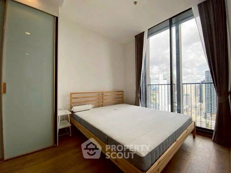 Modern bedroom with large window offering stunning city view
