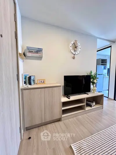 Modern living room with stylish TV stand and wall clock, showcasing sleek wooden flooring and contemporary decor.