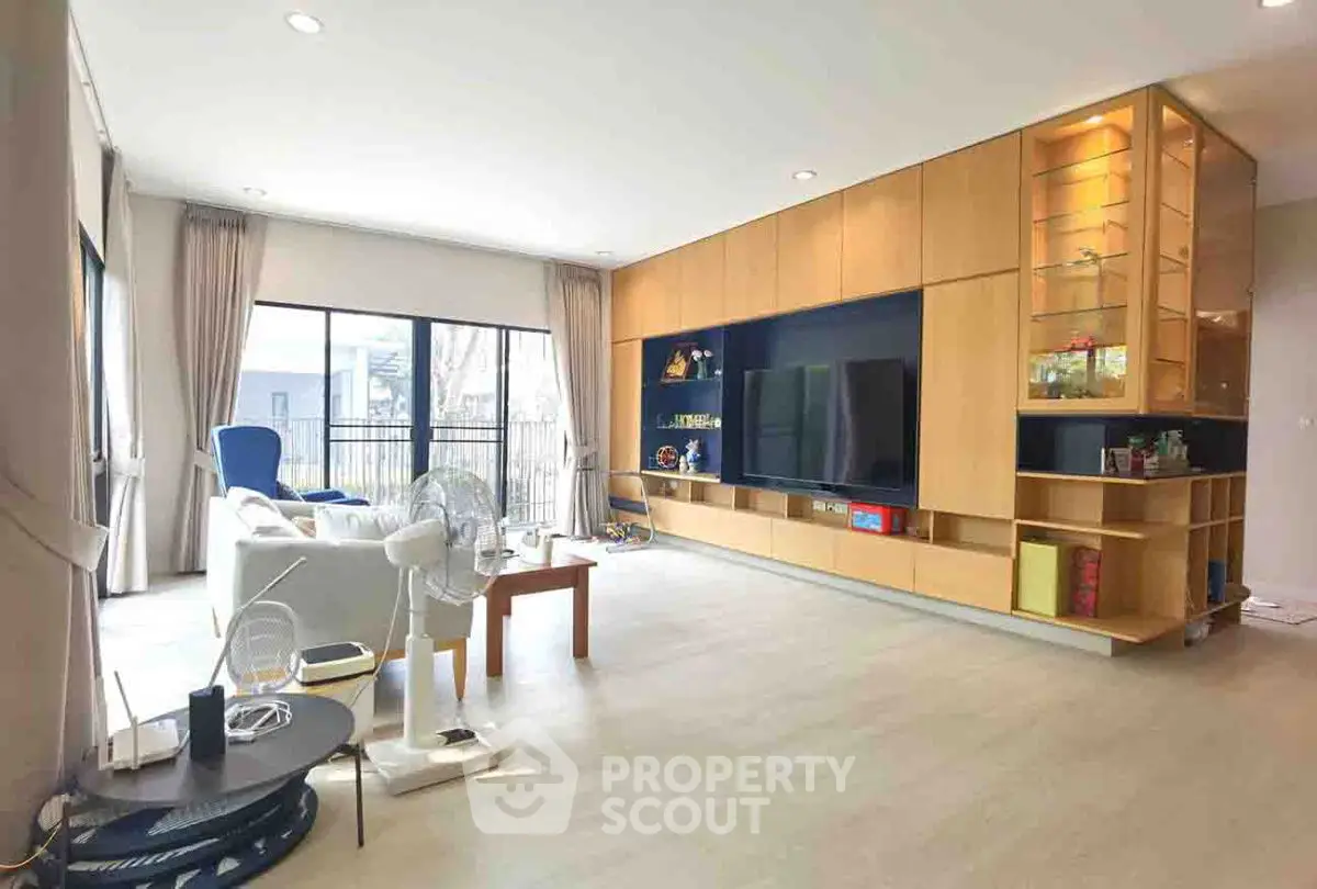 Spacious living room with modern entertainment center and large windows.