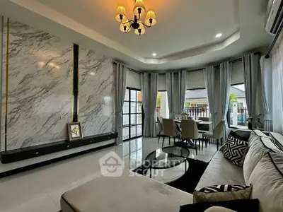 Luxurious living room with elegant marble wall and spacious dining area, featuring modern decor and ample natural light.