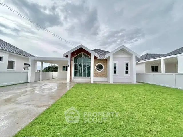 Stunning modern house with lush green lawn and spacious driveway under a cloudy sky.