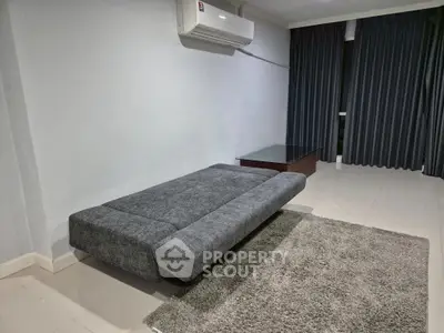 Modern minimalist living room with sleek gray sofa and air conditioning.