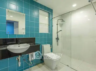 Modern bathroom with blue tiles and glass shower enclosure