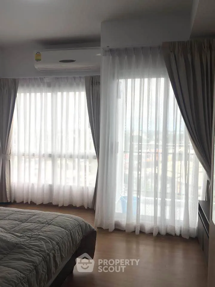 Bright bedroom with large windows and sheer curtains, offering ample natural light.