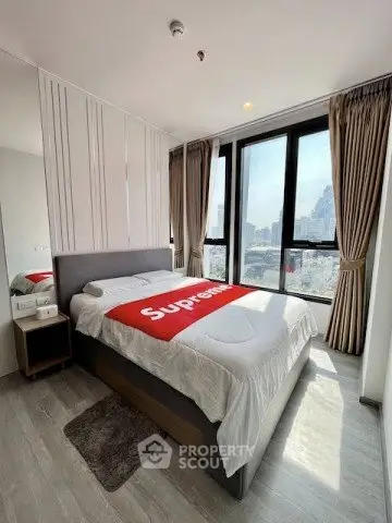 Modern bedroom with large windows and city view, featuring stylish decor and ample natural light.
