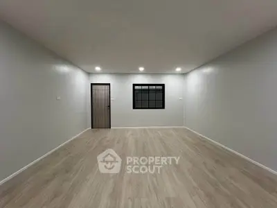 Spacious empty room with modern flooring and recessed lighting, ideal for customization.