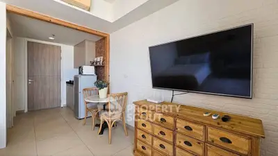 Cozy studio apartment with modern TV setup and compact dining area.
