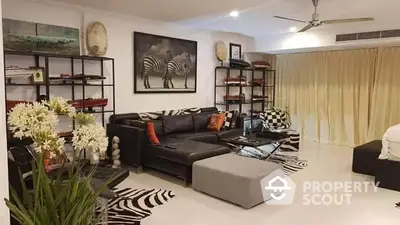 Spacious living room with elegant decor, featuring a large L-shaped sofa, zebra print rug, and tasteful art pieces, ideal for luxurious living.