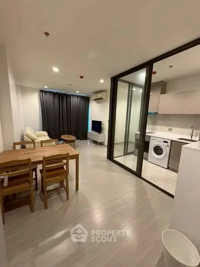 Modern open-plan living room with kitchen and dining area, featuring sleek design and natural light.