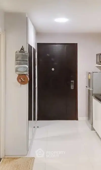 Modern apartment entrance with sleek kitchen and stainless steel fridge