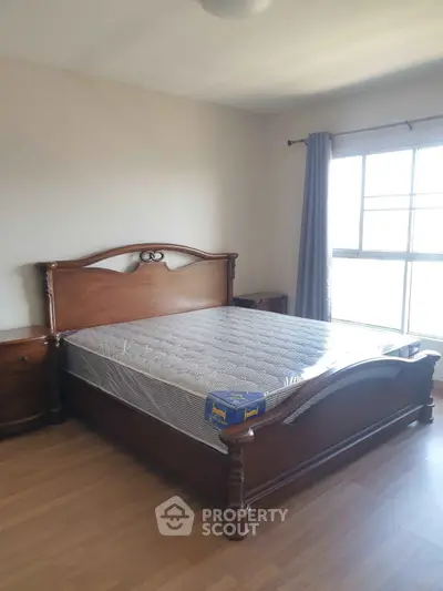 Spacious bedroom with elegant wooden bed and large window for natural light.