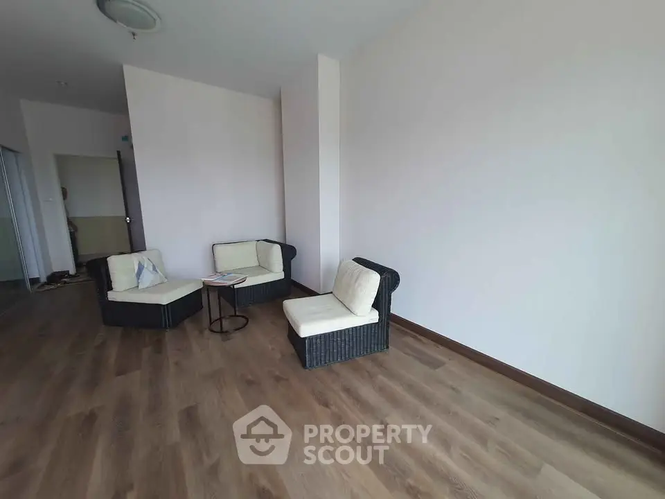 Spacious living room with modern wicker furniture and wooden flooring, perfect for relaxation.
