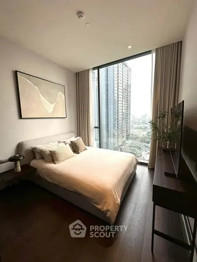 Luxurious bedroom with floor-to-ceiling window offering stunning city views, modern decor, and elegant furnishings.