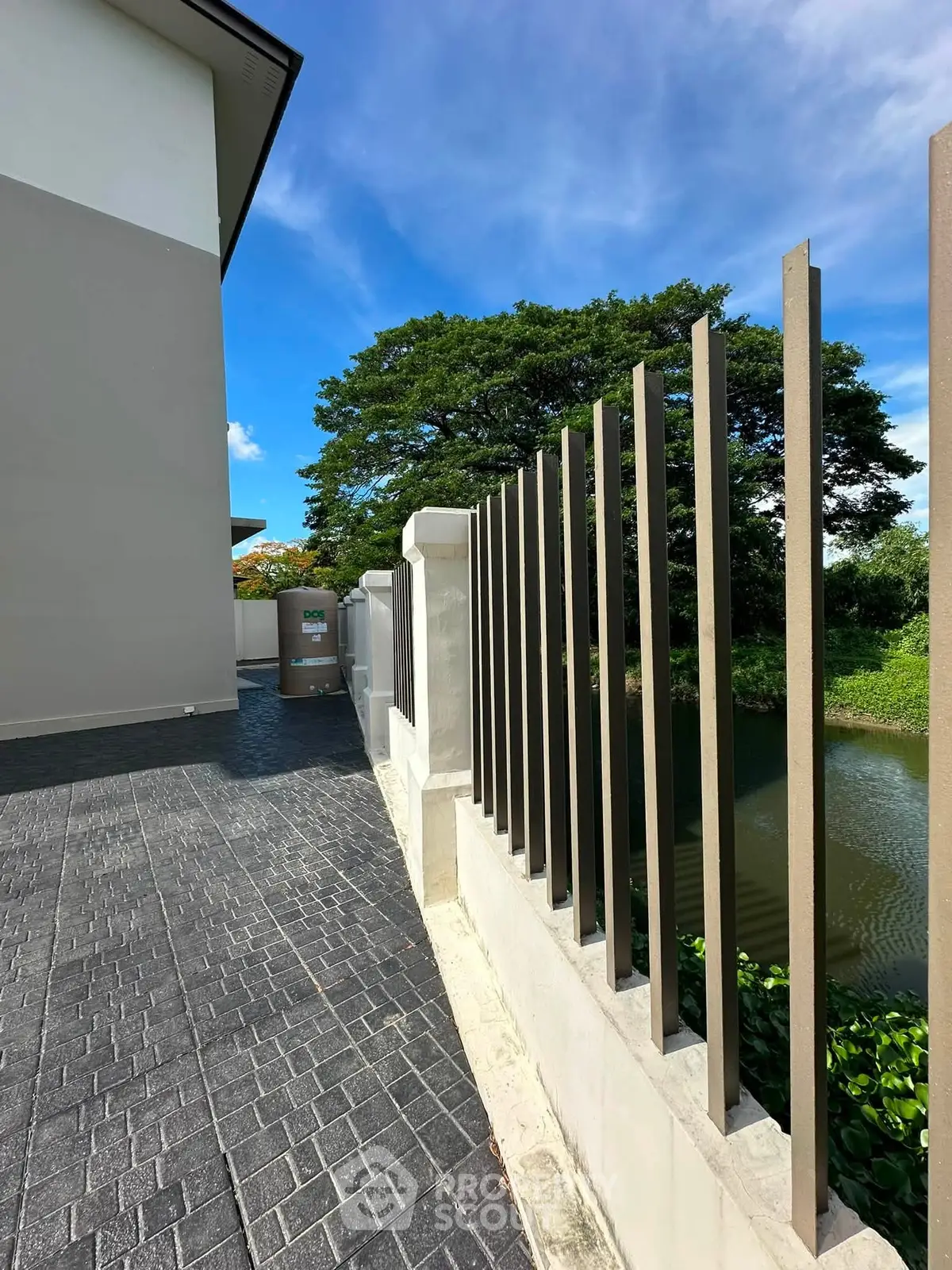 Modern building exterior with sleek fence and scenic water view, perfect for serene living.