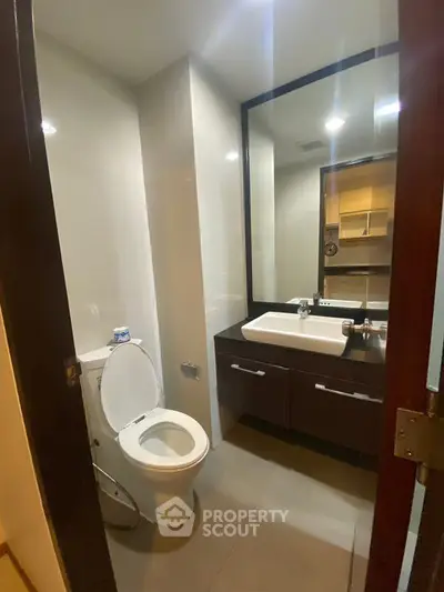 Modern bathroom with sleek fixtures and large mirror in a contemporary home.