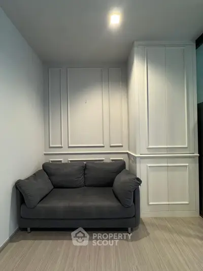 Cozy living room corner with elegant paneling and plush gray sofa, perfect for relaxation.
