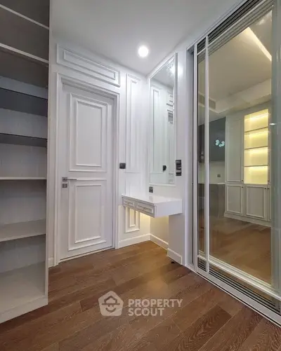 Elegant interior with wooden flooring and built-in shelving, featuring a modern sliding glass door.