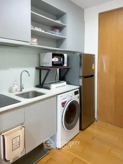 Modern compact kitchen with washing machine and stainless steel fridge