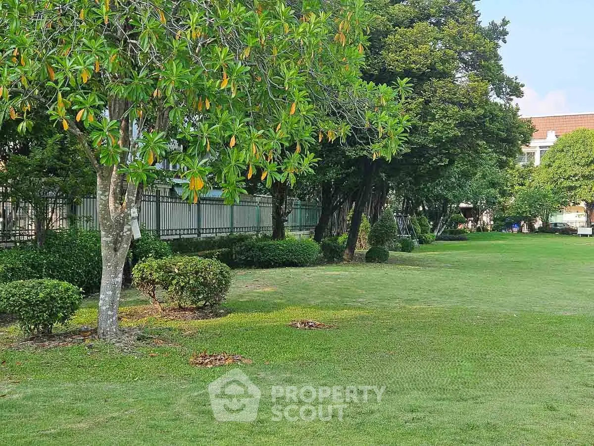 Lush green garden area with trees and manicured lawn in a residential complex.