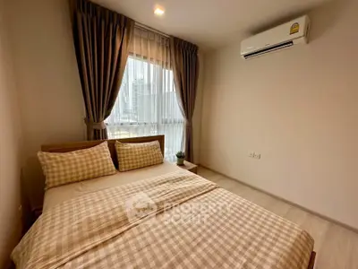 Cozy bedroom with large window and air conditioning in modern apartment.