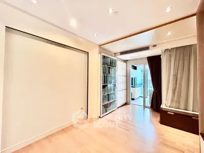 Spacious modern living room with wooden flooring and large windows for natural light.