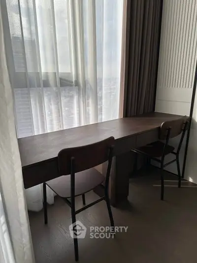 Modern study area with sleek desk and chairs by a large window with city view.