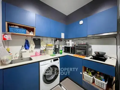 Modern compact kitchen with blue cabinets and integrated washing machine