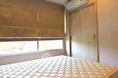 Cozy bedroom with large window and built-in wardrobe, featuring a comfortable mattress and air conditioning.